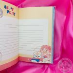 Hoja rayada decorada con un marco liso color amarillo y dibujo de chica kawaii con perrito en esquina inferior derecha.