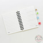 Cuaderno abierto, hojas rayadas.