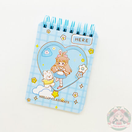 Libreta de color celeste, decorada con estampado de dibujos, chica kawaii en el centro envuelta en un corazón, flores, destellos y un conejo.