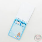 Libreta abierta dejando ver sus hojas estampadas lisas. Misma chica kawaii de la tapa con conejo.