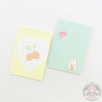 Dos juegos de hojas estampadas rayadas. El de la izquierda de color amarillo con blanco en el centro. El de la derecha de color verde. Los dos están decorados con dibujos, izquierda limones, derecha conejo y frutilla.